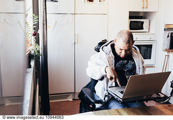 Disabled male using laptop while sitting on wheelchair at recording studio