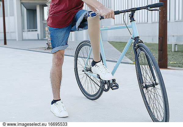 Disabled man riding bicycle on street
