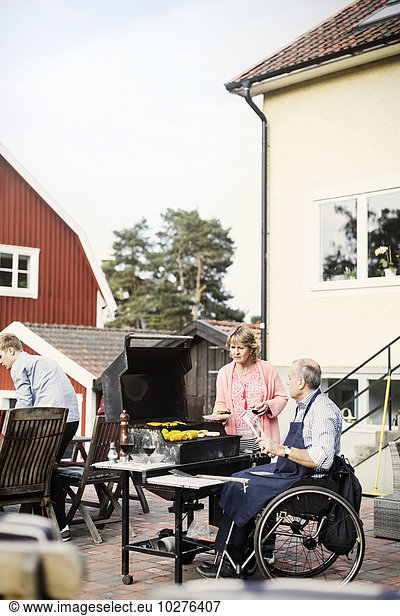 Disabled man with family barbecuing at yard