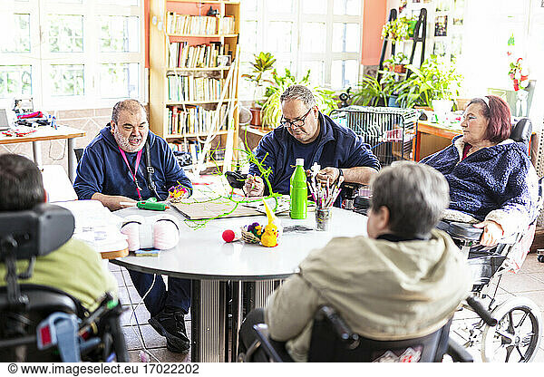 Disabled people doing craft at table in nursing home