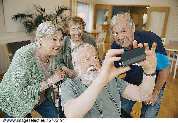 Disabled senior man taking selfie with friends at retirement home