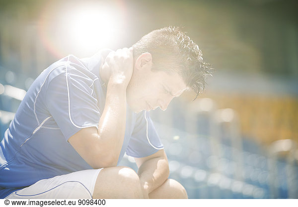 Disappointed soccer player sitting in stadium