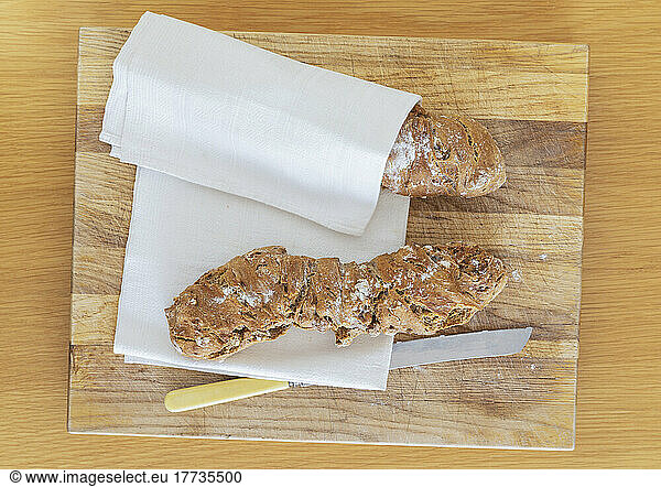 Dish towel and fresh homemade pain paillasse bread on wooden cutting board