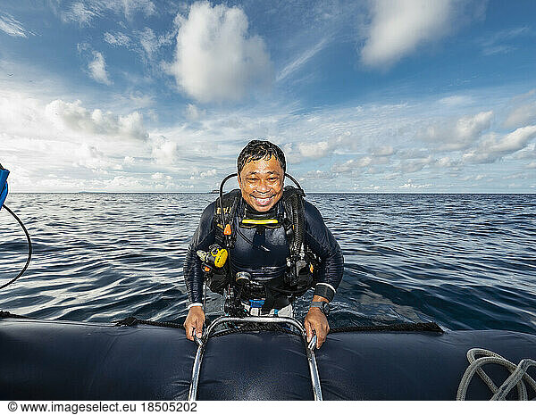 Diver climbing into dinghy after a dive in Banda Sea