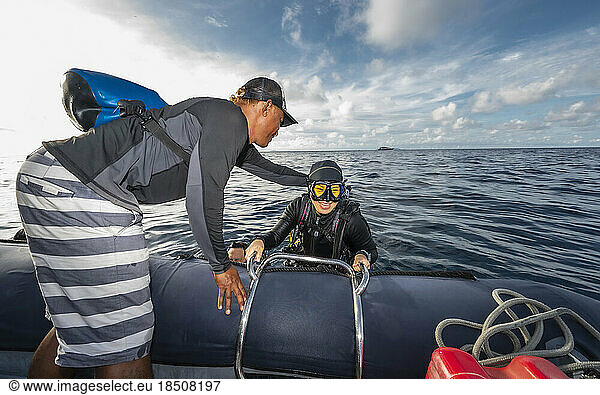 Diver climbing into dinghy after a dive in Banda Sea