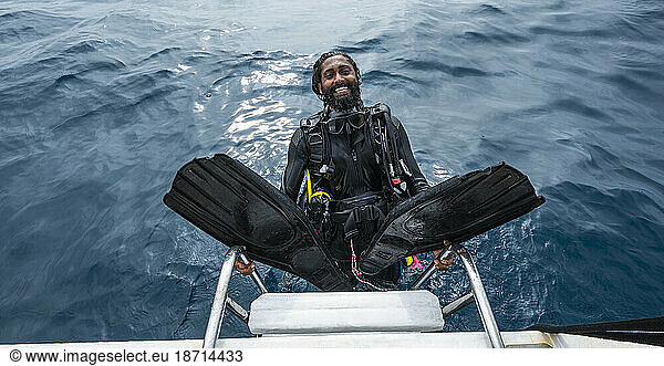 diver climbing up to a boat after finishing a dive in the Maldives