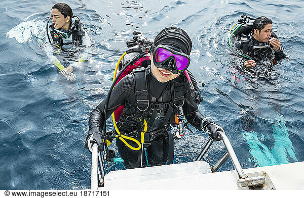 diver climbing up to a boat after finishing a dive in the Maldives