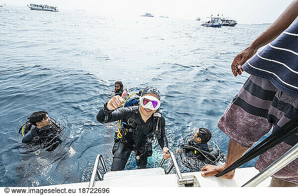 diver climbing up to a boat after finishing a dive in the Maldives