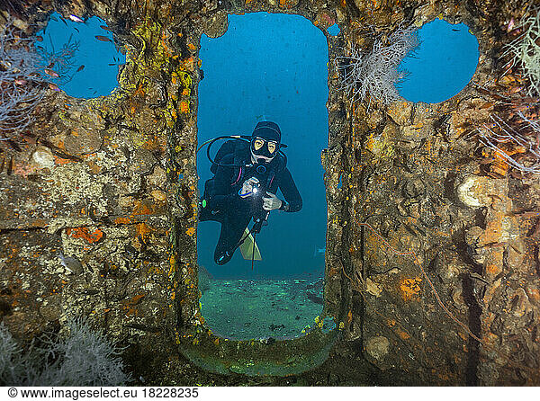 Diver exploring the wreck of the Sattakut close to Koh Tao