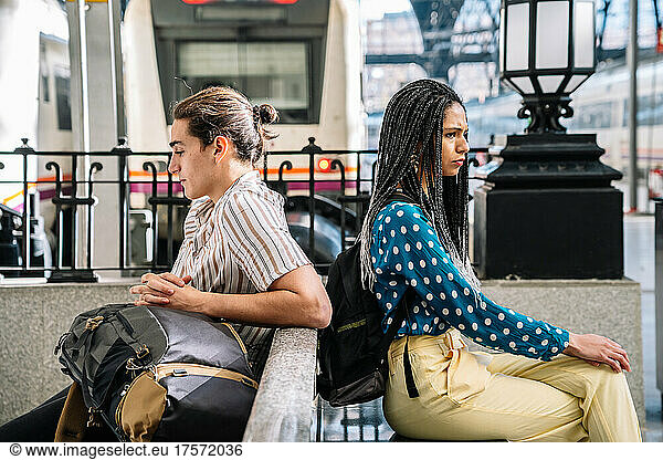 Diverse angry couple sitting in railway station