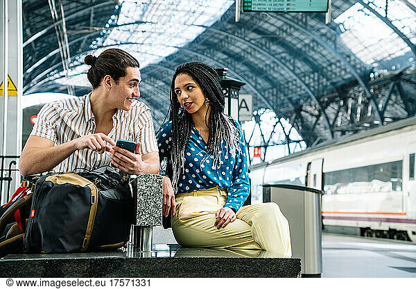 Diverse couple browsing smartphone in railway station