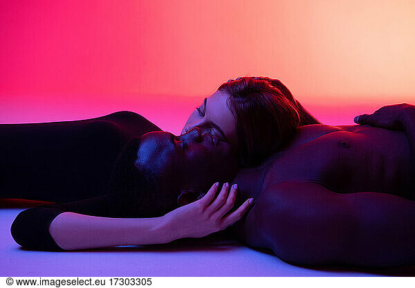 Diverse couple in love relaxing on studio floor