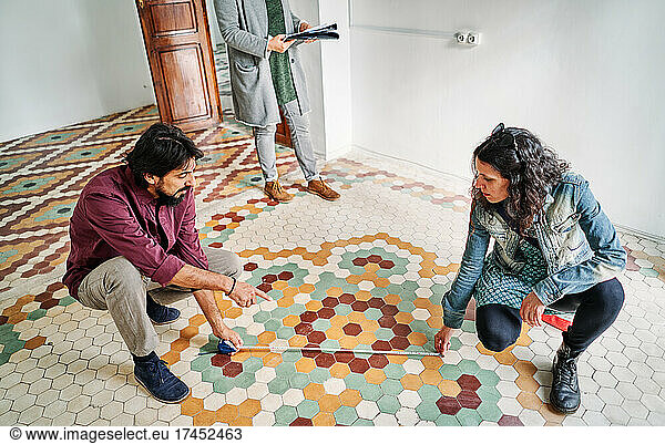 Diverse Couple Measuring Apartment Near Realtor