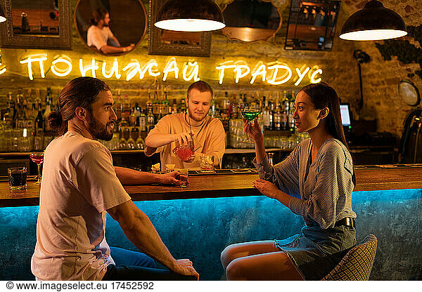 Diverse couple talking near barman