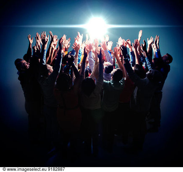 Diverse group reaching for bright light