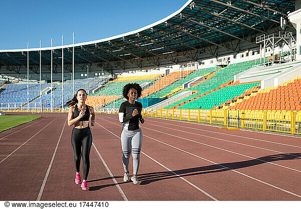 Diverse sportswomen jogging on stadium
