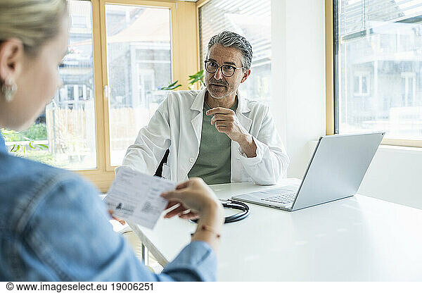Doctor advising patient reading medical report in clinic