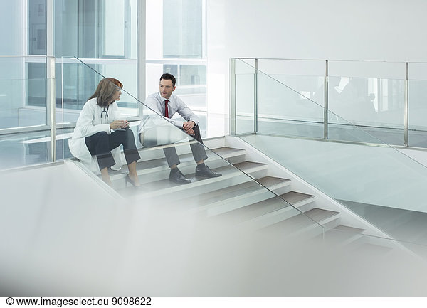 Doctor and administrator talking on hospital stairs