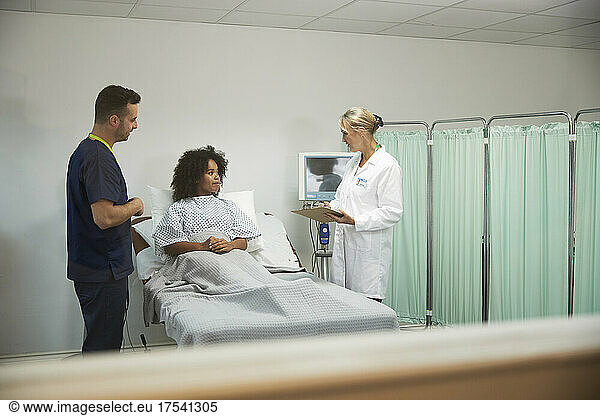 Doctor and nurse discussing with patient in medical room at hospital