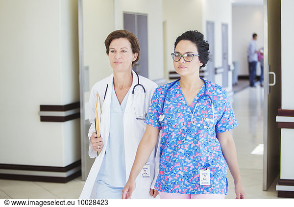 Doctor and nurse walking together in hospital corridor
