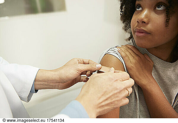 Doctor applying adhesive bandage on patient's arm in medical room