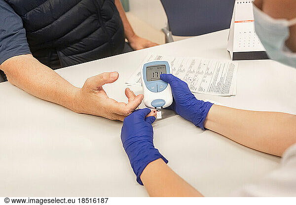 Doctor checking blood sugar level of patient at clinic