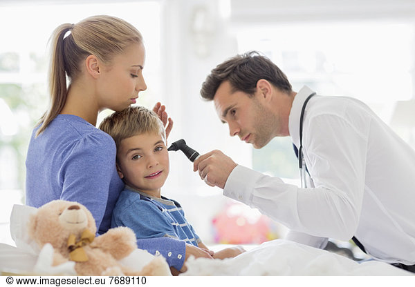 Doctor examining boy's ear at house call