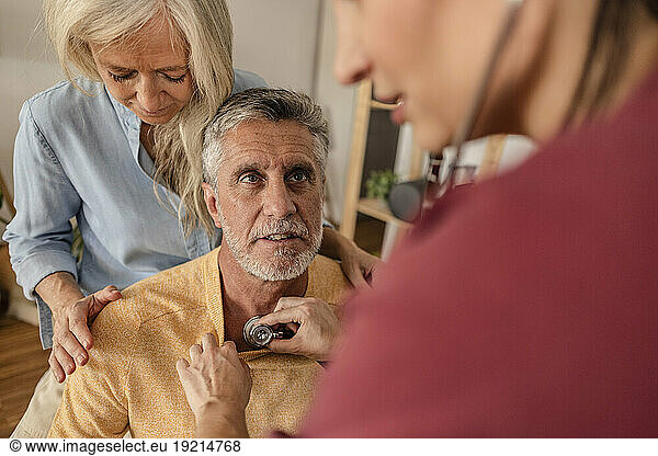 Doctor examining mature patient at home