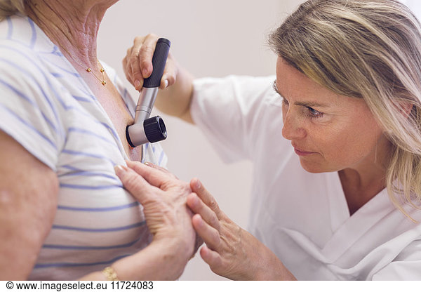 Doctor examining senior woman's skin