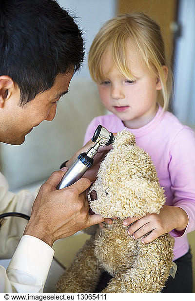 Doctor examining teddy bears ear at house call
