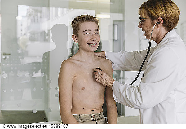 Doctor examining teenage boy with a stethoscope