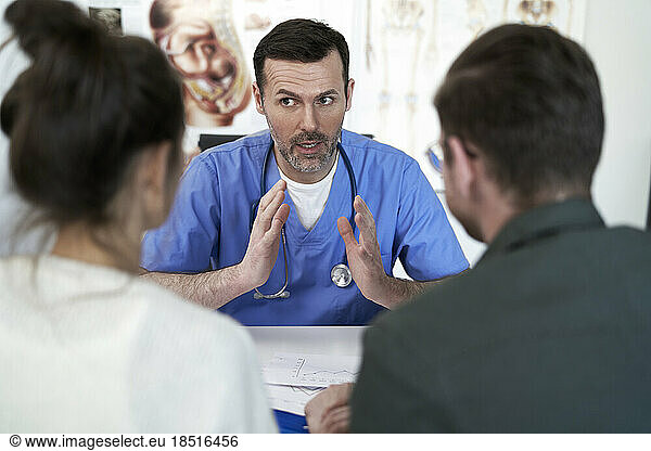 Doctor explaining and having discussion with couple in clinic