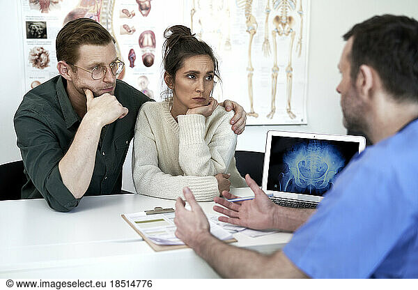Doctor explaining couple sitting in clinic