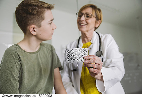 Doctor explaining medication to teenage boy in medical practice