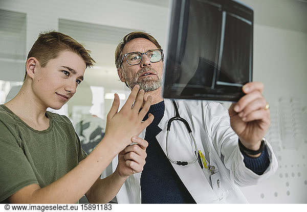Doctor explaining to teenage boy in medical practice