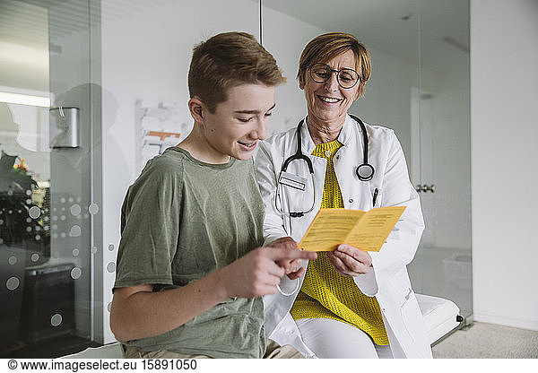 Doctor explaining vaccination to teenage boy in medical practice