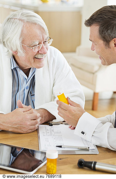 Doctor giving medication to older patient at house call