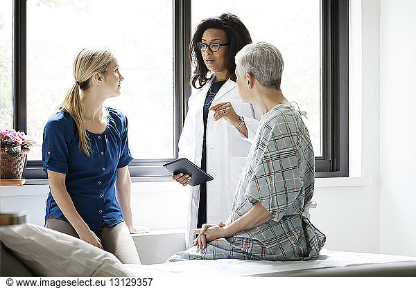 Doctor having discussing with woman and mature female patient in hospital