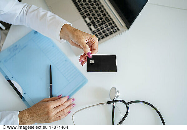 Doctor holding card above desk in medical practice