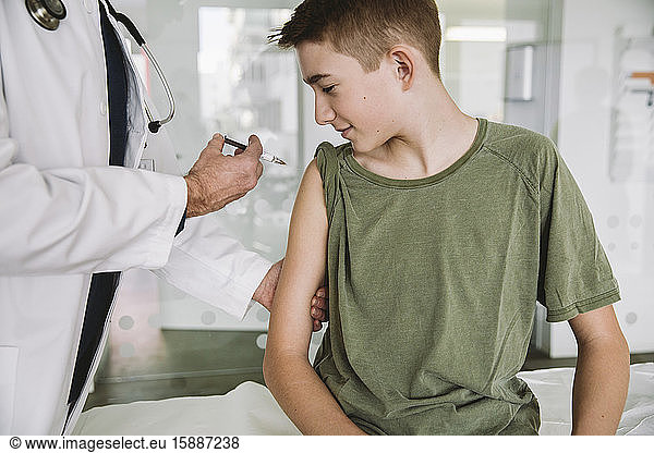 Doctor injecting a vaccine into teenager?s arm