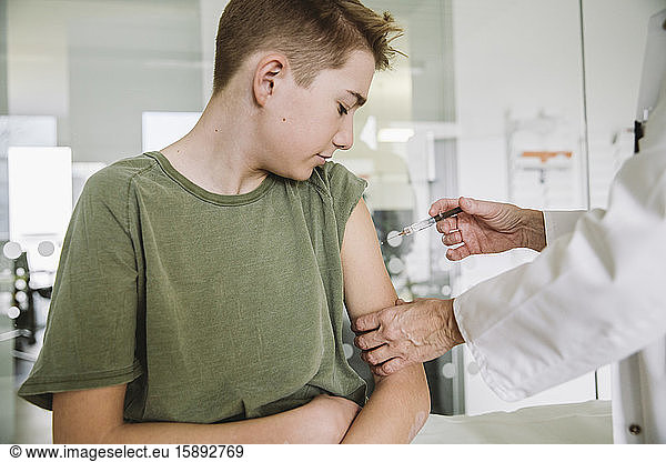 Doctor injecting vaccine into arm of teenager