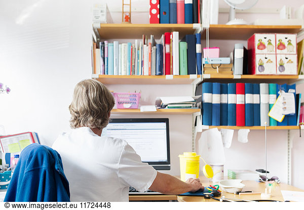 Doctor looking at computer screen in examination room