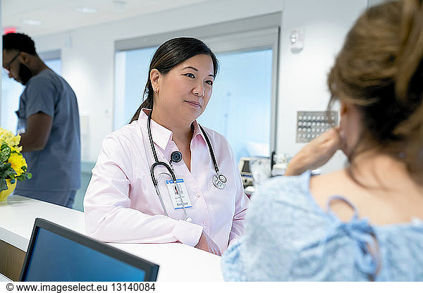 Doctor looking at female colleague with male coworker in background