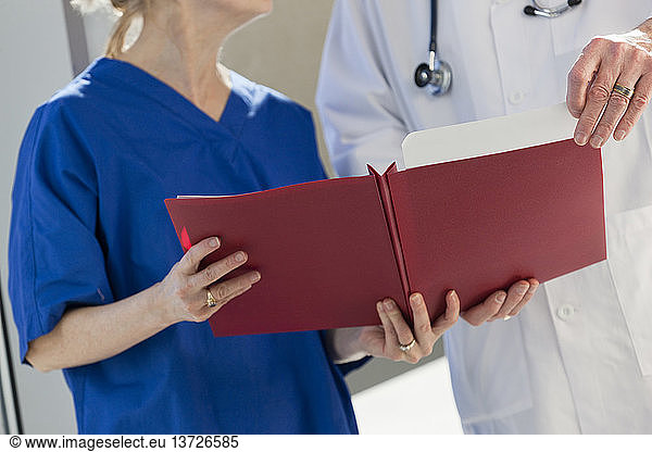Doctor looking at files hold by a nurse
