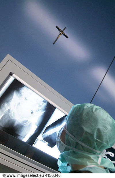 Doctor looking at x-rays with a crucifix on a blue wall