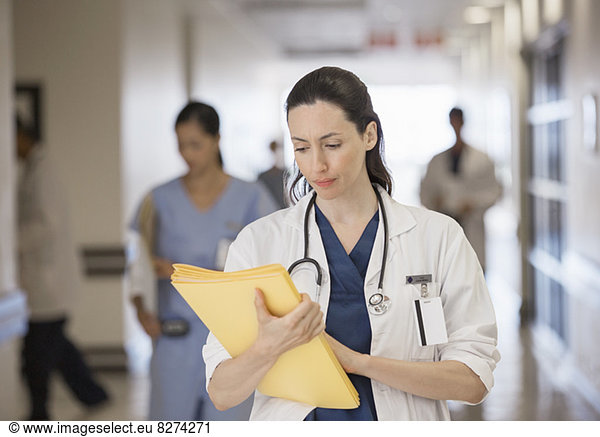 Doctor looking down at folder in hospital corridor