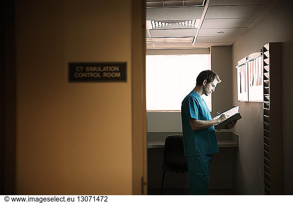 Doctor reading reports while standing in hospital ward