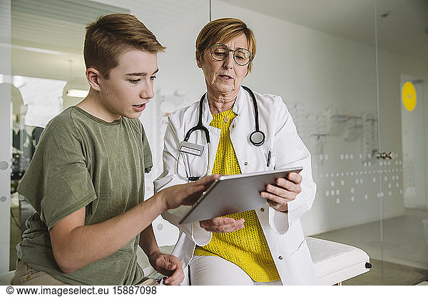 Doctor showing tablet to teenage boy in medical practice