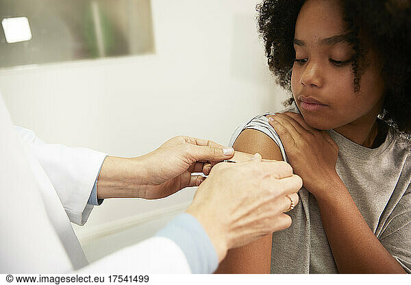 Doctor sticking adhesive bandage on patient arm