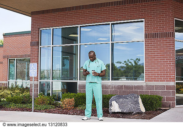Doctor using phone while standing outside hospital